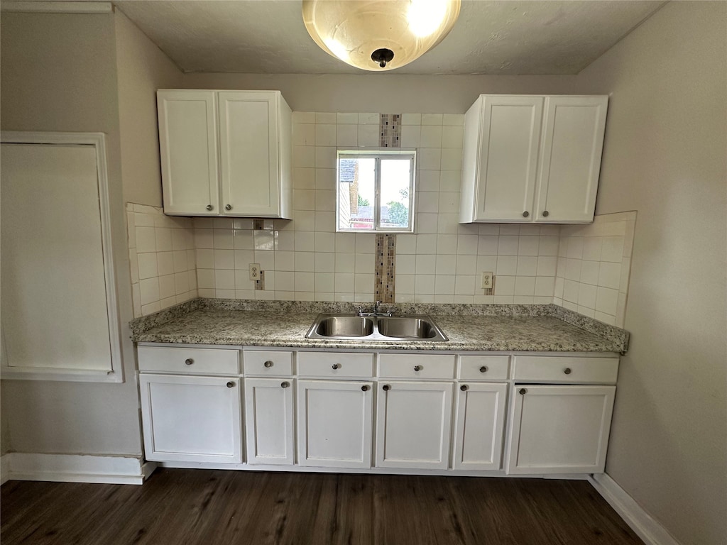 kitchen featuring sink, dark hardwood / wood-style floors, white cabinets, light stone countertops, and backsplash