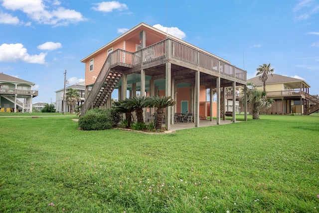 back of house featuring a wooden deck, a lawn, and a patio