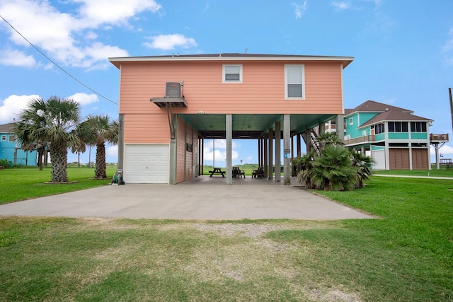 rear view of house featuring a carport, a garage, and a lawn