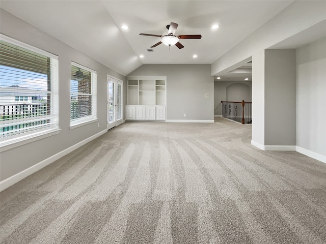 interior space with ceiling fan, light colored carpet, vaulted ceiling, and a healthy amount of sunlight