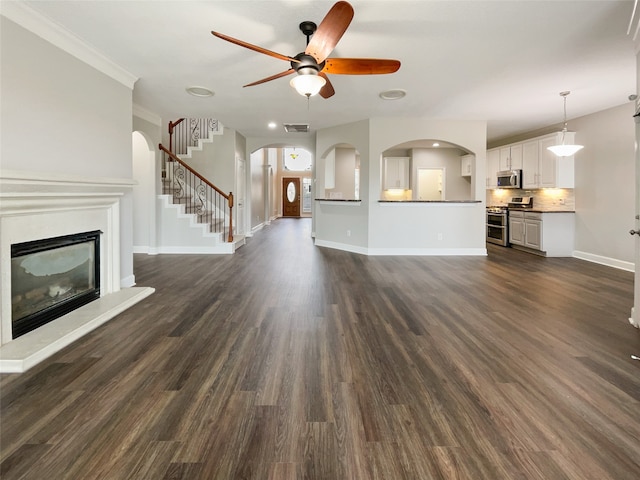 unfurnished living room with ornamental molding, dark wood-type flooring, and ceiling fan