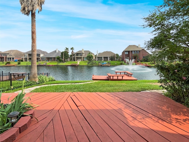 wooden terrace featuring a water view and a lawn