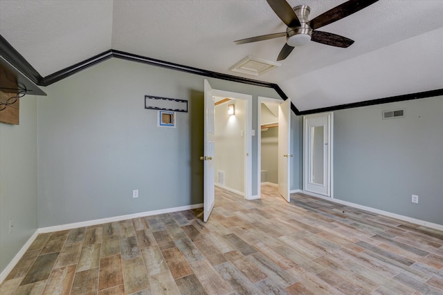 interior space with lofted ceiling, ceiling fan, a textured ceiling, and light wood-type flooring