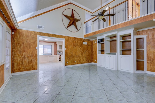 unfurnished living room with ornamental molding, light tile patterned floors, and wooden walls