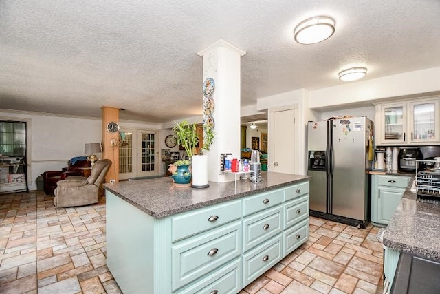 kitchen with stainless steel fridge with ice dispenser, decorative columns, light tile flooring, and a textured ceiling