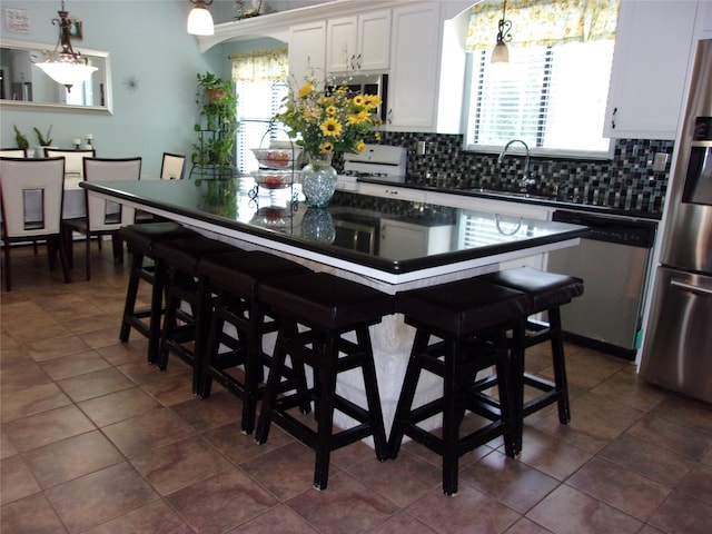 kitchen featuring tasteful backsplash, white cabinets, a wealth of natural light, and appliances with stainless steel finishes