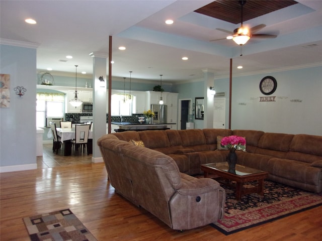 living room featuring hardwood / wood-style floors, ceiling fan, a tray ceiling, and crown molding