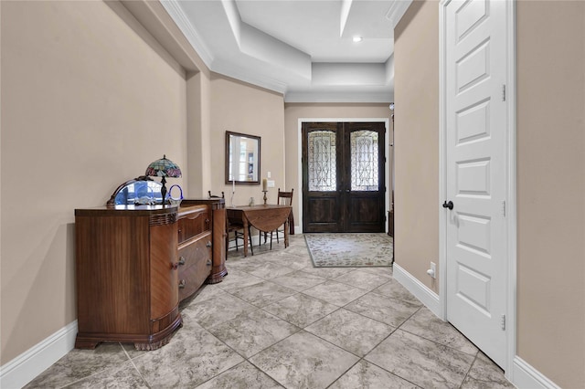 foyer featuring a raised ceiling, ornamental molding, and french doors