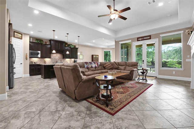 living room with ceiling fan, french doors, and a tray ceiling