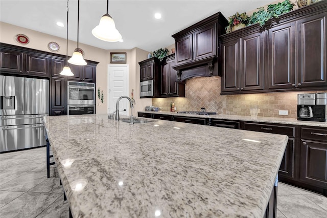 kitchen featuring dark brown cabinets, stainless steel appliances, a kitchen island with sink, and sink