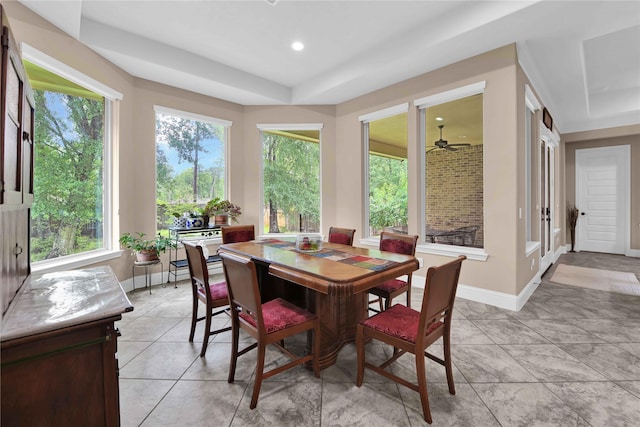 tiled dining area with a tray ceiling and ceiling fan