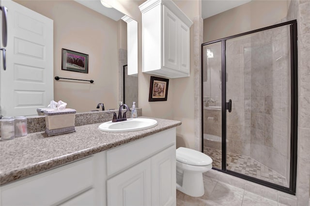 bathroom featuring tile patterned flooring, vanity, toilet, and walk in shower