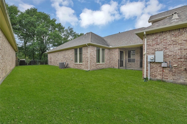 back of house with central AC and a lawn