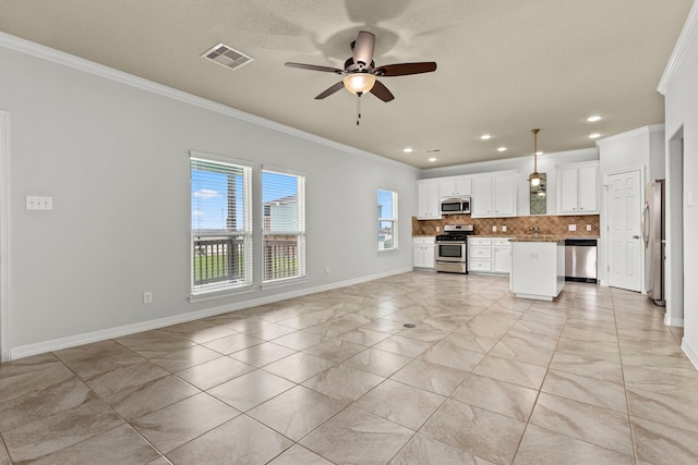 kitchen featuring white cabinets, appliances with stainless steel finishes, decorative light fixtures, a kitchen island, and ornamental molding