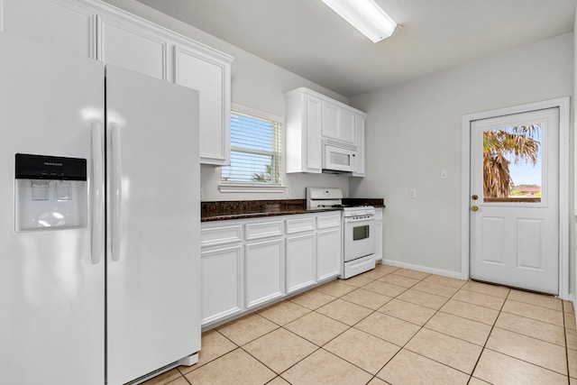 kitchen with white cabinets, white appliances, light tile patterned flooring, and dark stone countertops