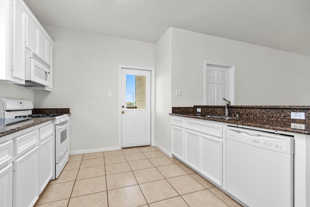 kitchen featuring dark stone countertops, white cabinetry, sink, and white appliances