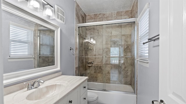 full bathroom featuring a healthy amount of sunlight, bath / shower combo with glass door, toilet, and vanity