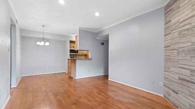 unfurnished living room featuring a chandelier, light hardwood / wood-style flooring, and crown molding