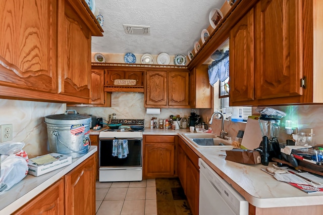 kitchen with a textured ceiling, white appliances, sink, tasteful backsplash, and light tile floors