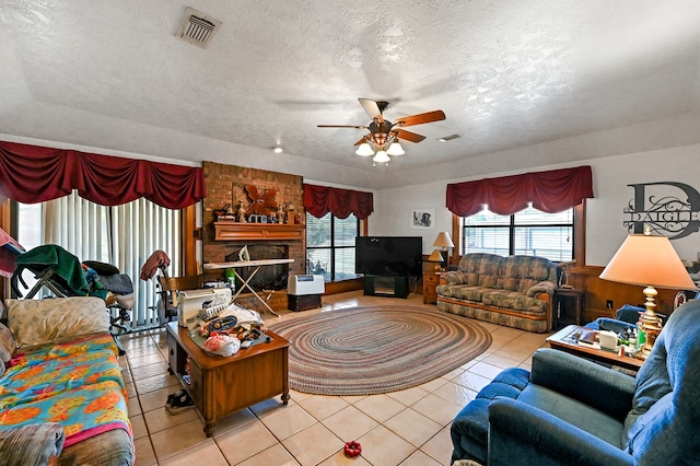 tiled living room with a brick fireplace, ceiling fan, and a textured ceiling