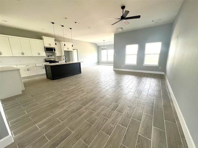 kitchen featuring a kitchen island with sink, wood-type flooring, stainless steel appliances, white cabinetry, and ceiling fan