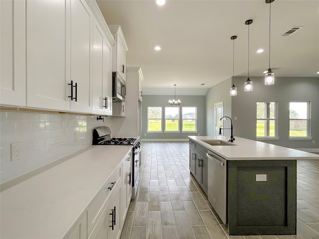 kitchen with stainless steel appliances, tasteful backsplash, light countertops, white cabinetry, and a sink