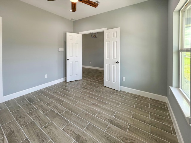 empty room featuring wood finish floors, plenty of natural light, and baseboards