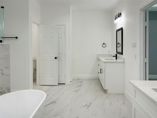 full bathroom featuring baseboards, a sink, marble finish floor, a freestanding bath, and two vanities