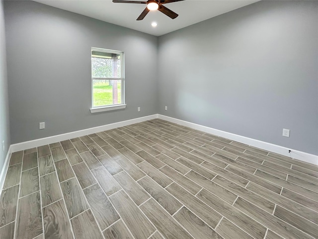 empty room with wood tiled floor, baseboards, and a ceiling fan