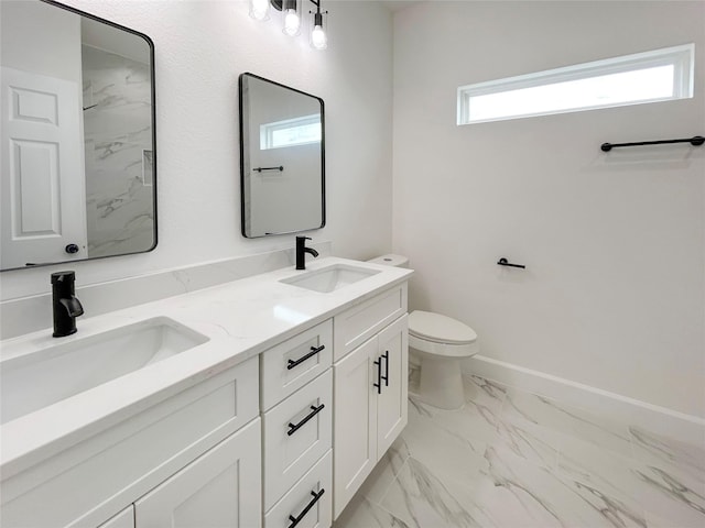 bathroom featuring toilet, marble finish floor, double vanity, and a sink