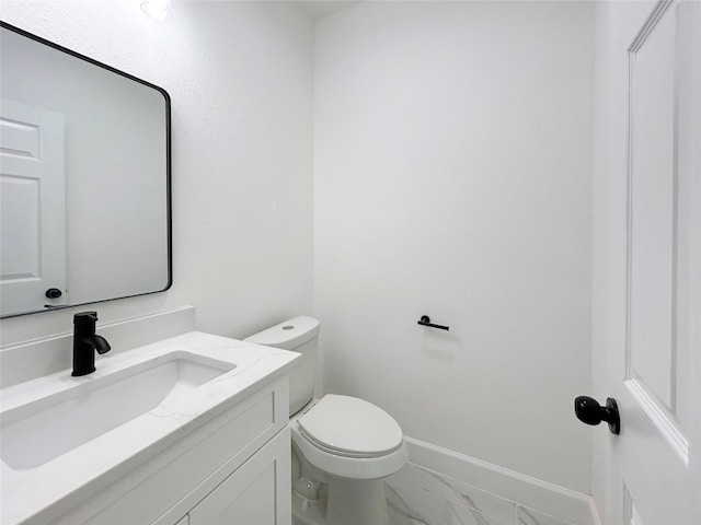 bathroom featuring toilet, marble finish floor, baseboards, and vanity