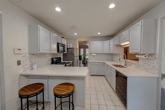 kitchen featuring black appliances, sink, kitchen peninsula, white cabinetry, and a breakfast bar area