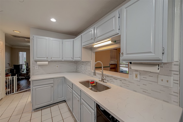 kitchen with light tile patterned flooring, sink, white cabinetry, black dishwasher, and crown molding