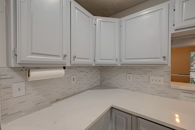 kitchen featuring light stone counters, tasteful backsplash, and white cabinetry