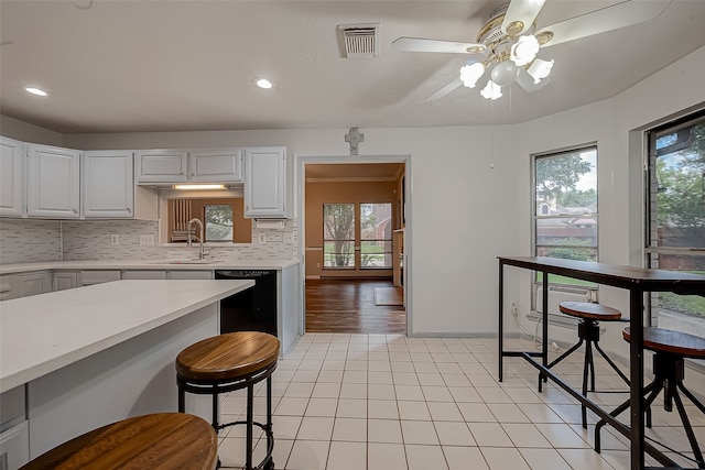 kitchen featuring dishwasher, plenty of natural light, ceiling fan, and white cabinetry