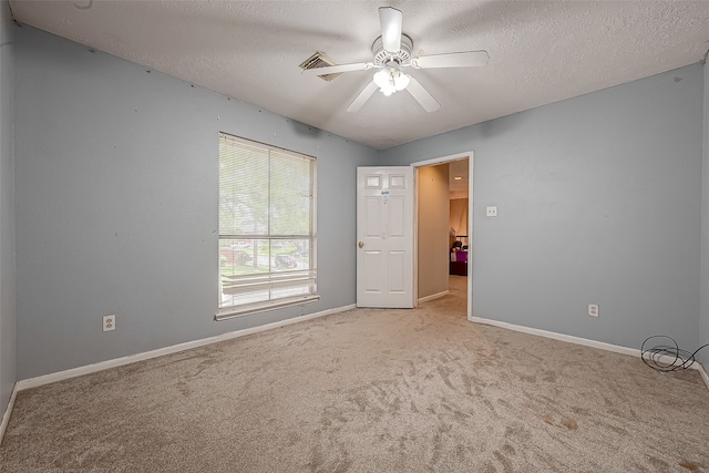 empty room featuring light colored carpet, a textured ceiling, and ceiling fan