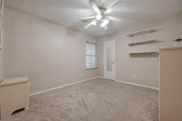 empty room with light carpet, ceiling fan, and a textured ceiling