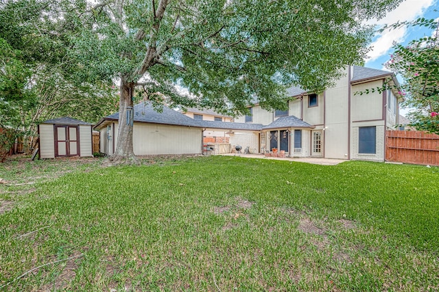 rear view of property with a yard, a storage shed, and a patio area