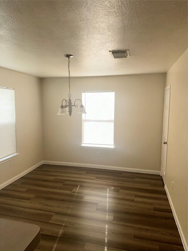 spare room featuring plenty of natural light, a chandelier, and dark hardwood / wood-style floors