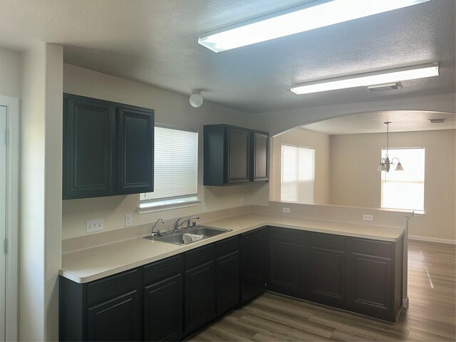 kitchen featuring sink, hanging light fixtures, an inviting chandelier, dark hardwood / wood-style flooring, and kitchen peninsula