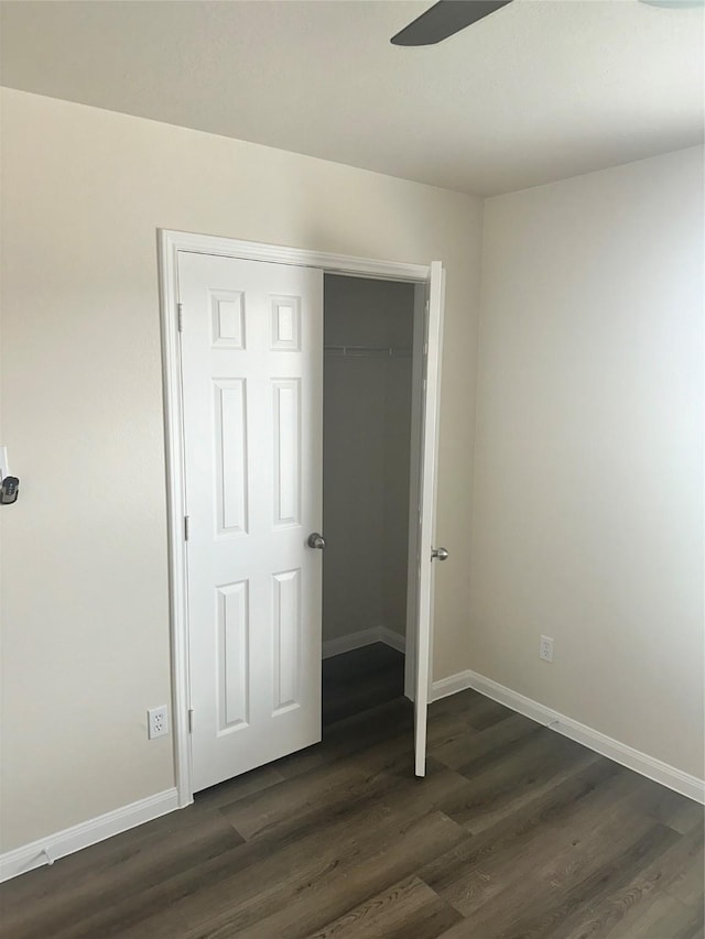 unfurnished bedroom with ceiling fan, a closet, and dark wood-type flooring