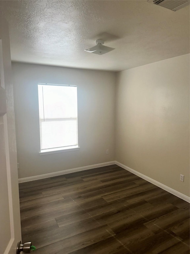 unfurnished room featuring a textured ceiling and dark hardwood / wood-style flooring