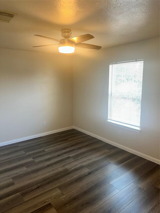 empty room featuring a textured ceiling, ceiling fan, and dark wood-type flooring