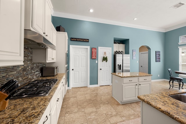 kitchen with stainless steel fridge, a kitchen island, white cabinets, backsplash, and light tile floors