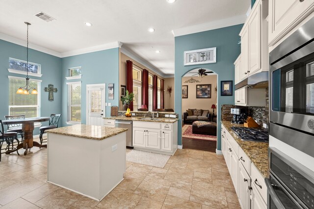 kitchen featuring light stone countertops, stainless steel appliances, light tile floors, ornamental molding, and white cabinetry