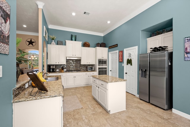 kitchen with backsplash, appliances with stainless steel finishes, white cabinetry, and a center island