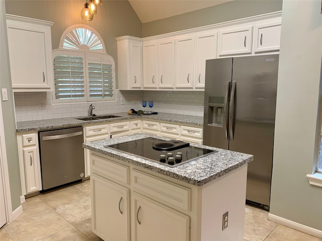 kitchen featuring appliances with stainless steel finishes, tasteful backsplash, light stone counters, sink, and a center island