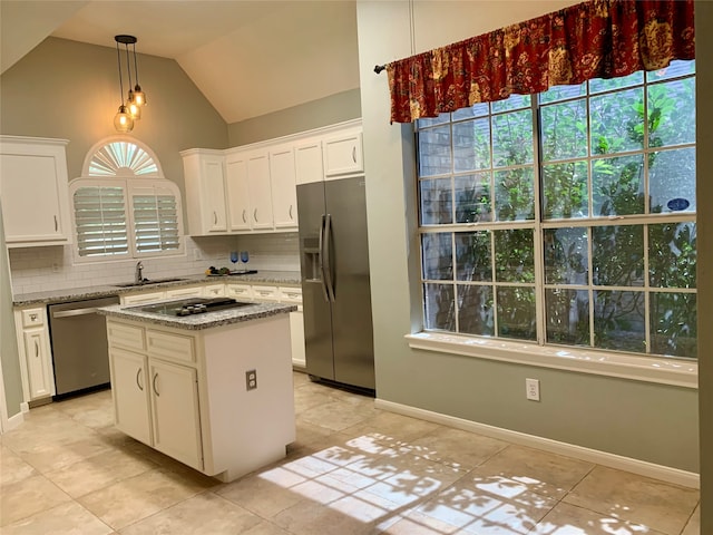 kitchen with backsplash, vaulted ceiling, appliances with stainless steel finishes, a kitchen island, and white cabinetry