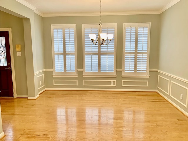 unfurnished dining area featuring light hardwood / wood-style flooring, crown molding, and a notable chandelier