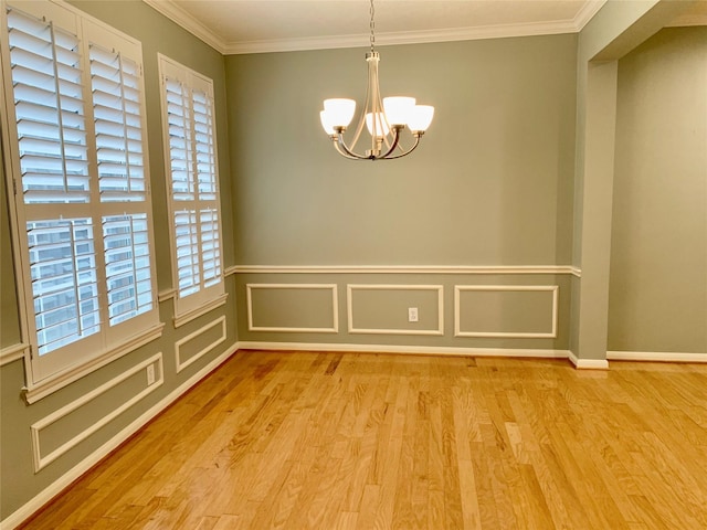 empty room featuring crown molding, a notable chandelier, and light wood-type flooring